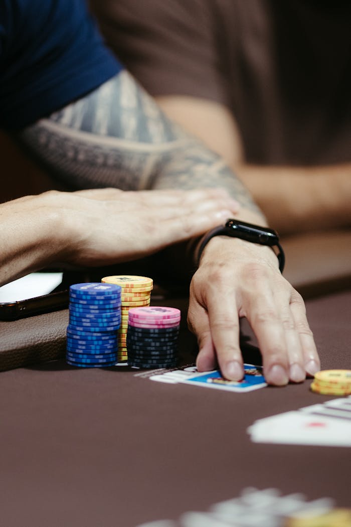 services-03 Detailed close-up of hands in a poker game, displaying colorful chips and cards on the table.