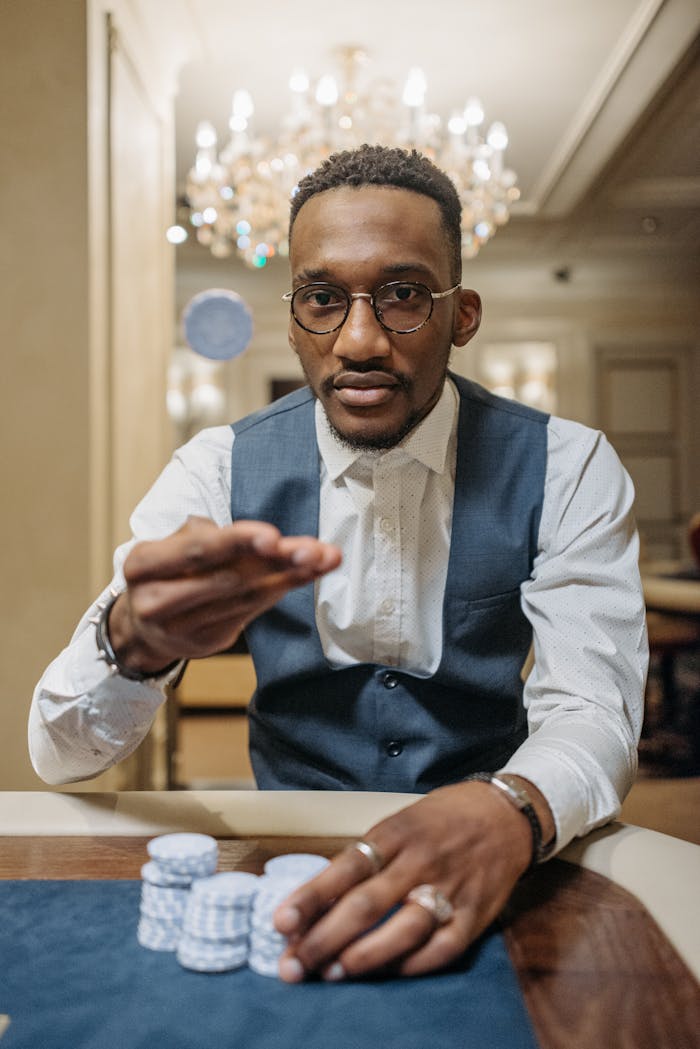 services-01 A focused African American man in a casino betting with poker chips, a chandelier in the background.